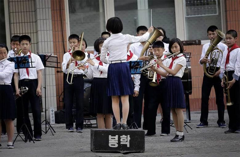 Μαθητική ορχήστρα παίζει σε δρόμο της Πιονγκγιάνγκ, αμέσως μετά το τέλος των μαθημάτων στις 16 Ιουνίου. Με το απολυτήριο του σχολείου οι αποφοιτήσαντες μπορούν να εγγραφούν σε κολέγια ή πανεπιστήμια