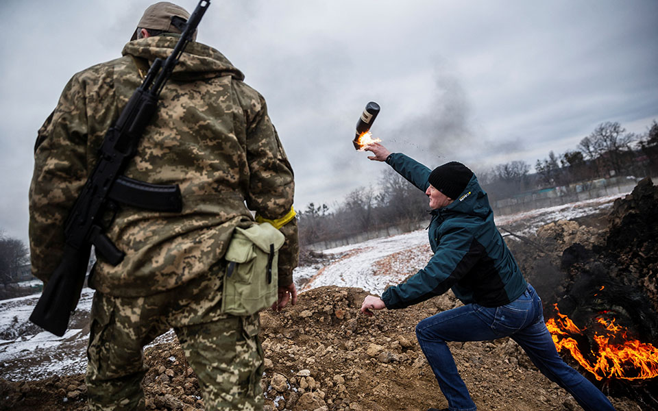 Πολίτης εκτοξεύει βόμβα μολότοφ υπό το βλέμμα Ουκρανού στρατιώτη.