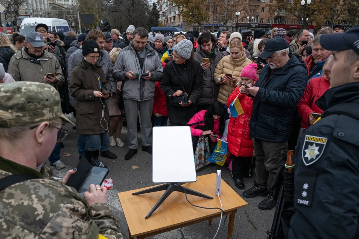Ουκρανοί μαζεύονται για παροχή ίντερνετ από τερματικό της Starlink.